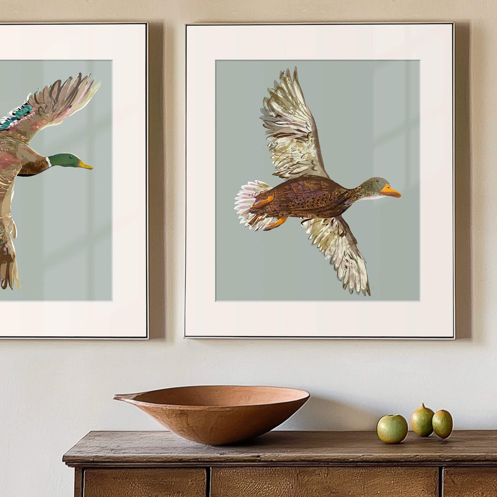 framed female mallard image on the wall above a weathered console table with art objects on it
