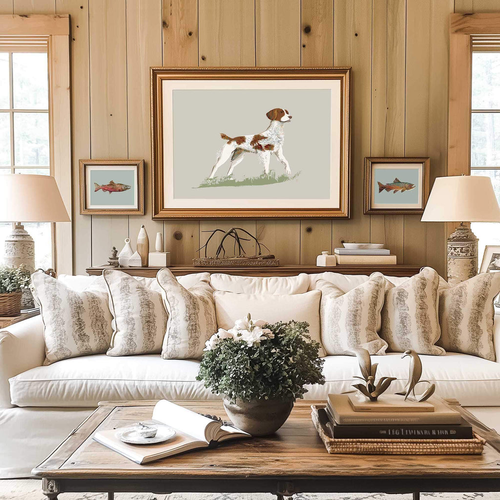 brittany dog art in a gilded frame in a traditional decor living room of a hunting lodge with warm wood walls and a white sofa