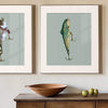 pair of framed fishing lure artworks over an antique wooden console table with a bowl and decorative fruit