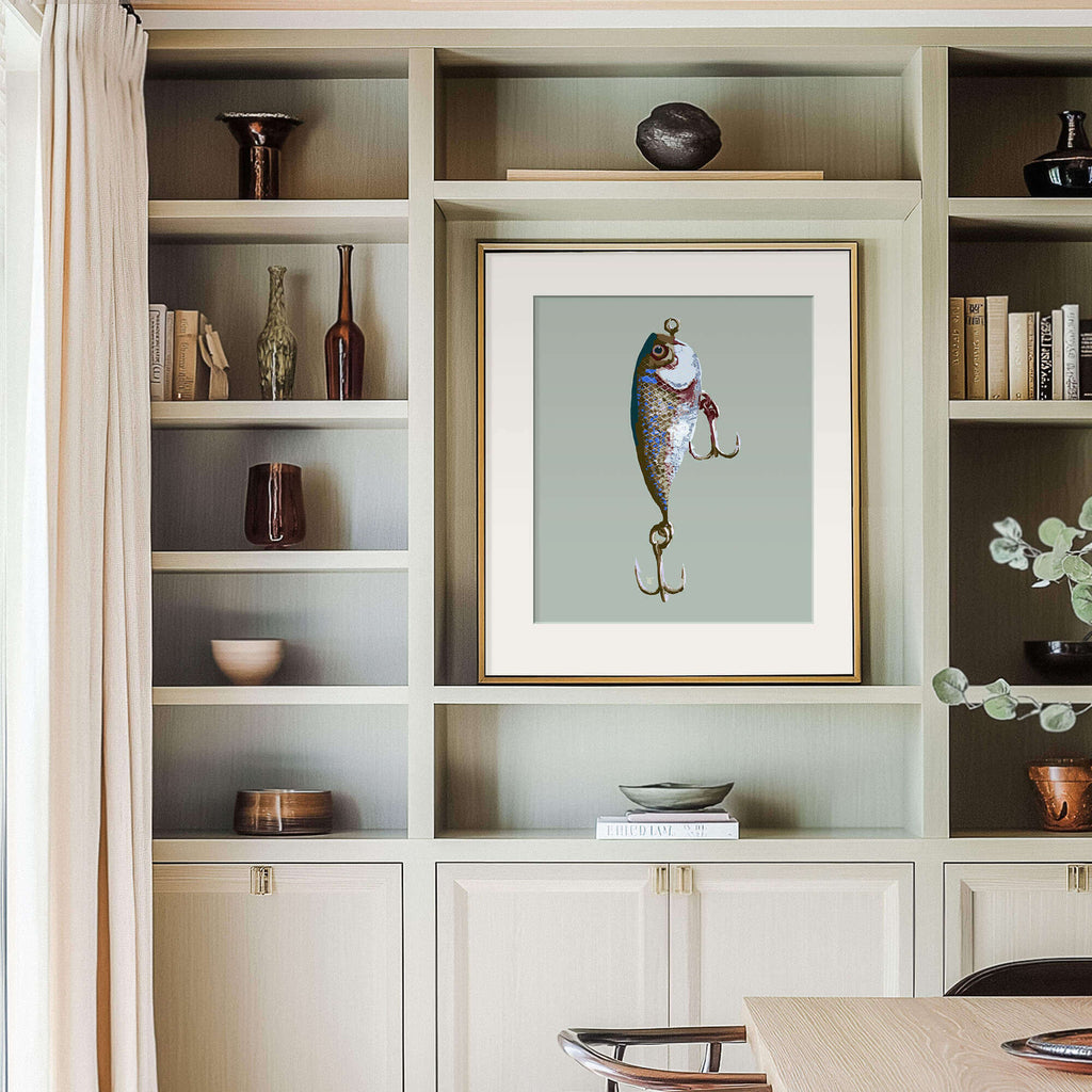 living room built-in shelving with art objects and a framed fishing lure drawing. the lake house decor has light wood and books