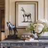 framed horse drawing above an antique table near other art objects