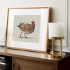 grey partridge in a brass frame in a man's home office